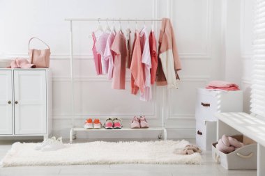 Askıda asılı farklı şık kıyafetler, aksesuarlar ve ayakkabılar.