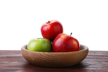 Kırmızı ve yeşil olgun elmalar kasede tahta masada beyaz arka planda