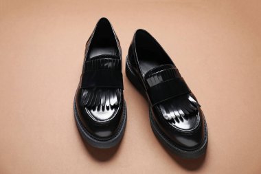 Kahverengi arka planda bir çift şık mokasen ayakkabı.