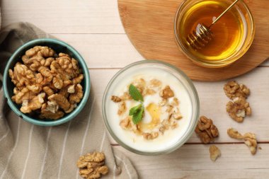 Beyaz ahşap masada servis edilen ballı ve cevizli lezzetli Yunan yoğurdu.