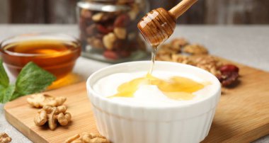 Yunan yoğurduna bal damlatıyor ve gri masada ceviz, yakın plan.