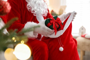 Noel Baba Noel ağacının yakınındaki çuvaldan hediyesini alıyor.