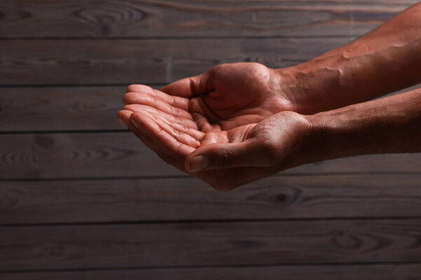 African-american man holding something on wooden background, closeup. Space for text