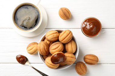 Lezzetli fındık şekilli kurabiyeler haşlanmış konsantre süt ile beyaz ahşap masada kahve ile servis edilir.