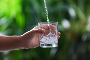 Bulanık yeşil arka planda su sıçratan kadın, yakın plan.