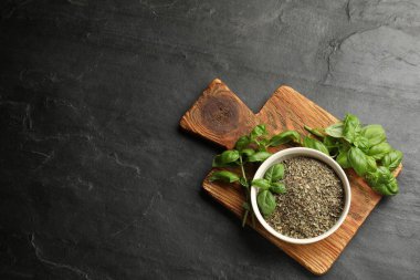 Kasede kuru fesleğen ve siyah desenli masada taze yeşil yapraklar. Metin için boşluk