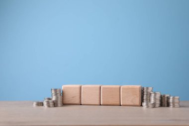 Boş küpler ve açık mavi arka planla masaya istiflenmiş bozuk paralar. Tasarım için boşluk