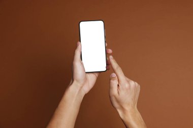 Kahverengi arka planda boş ekranlı akıllı telefon tutan adam, yakın plan. Tasarım için model