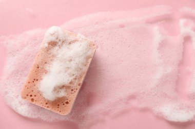 Pembe arka planda köpüklü mutfak süngeri.