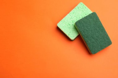 Turuncu arka planda mutfak süngerleri, üst manzara. Metin için boşluk