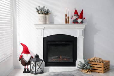 Christmas decor on fireplace and firewood near white wall indoors. Interior design