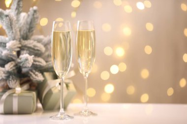 Mutlu Noeller ve mutlu yıllar. Köpüklü şaraplı flüt bardakları ve bulanık ışıklara karşı beyaz masada şenlikli bir dekor. Metin için boşluk