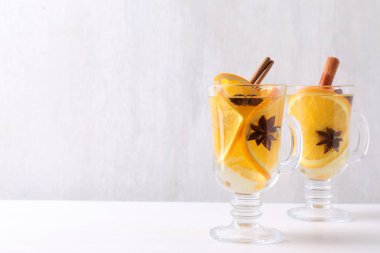 Baharatlı lezzetli şarap ve beyaz masada cam bardaklarda portakal dilimleri. Metin için boşluk