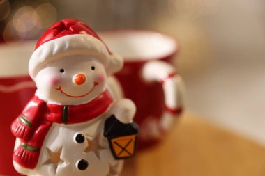 İçerideki bulanık ışıklara karşı sevimli kardan adam figürü, mesaj için yere yakın. Mutlu Noeller ve mutlu yıllar.