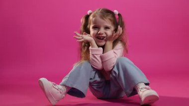 At kuyruklu mutlu küçük kız pembe arka planda eğleniyor.