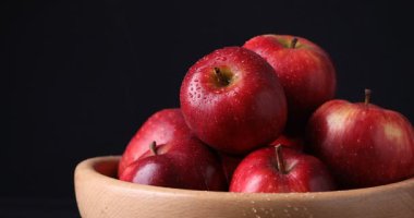 Olgun kırmızı elmaları siyah arka planda suyla kaplamak, yakın plan. Metin için boşluk