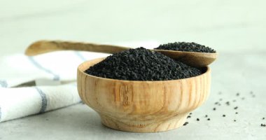 Gri masadaki ahşap kaseye aromatik siyah oyma döken kadın, yakın plan.