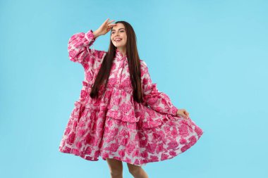 Açık mavi arka planda güzel giyimli bir kadın.