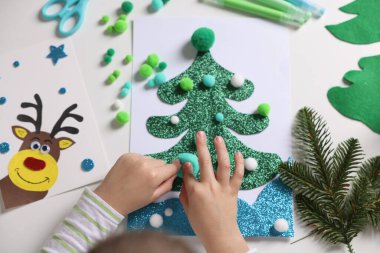 Küçük çocuk Noel kartpostalı hazırlıyor. Çocuk el yapımı.