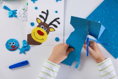 Küçük çocuk Noel kartpostalı hazırlıyor. Çocuk el yapımı.