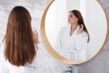 İçerideki aynanın yanında bornozlu güzel bir kadın.