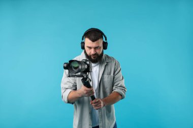 Açık mavi arkaplanda kameralı titreşim dengeleyici kullanan kameraman