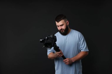 Kameraman siyah arkaplanlı, titreşimli dengeleyici kullanıyor. Metin için boşluk