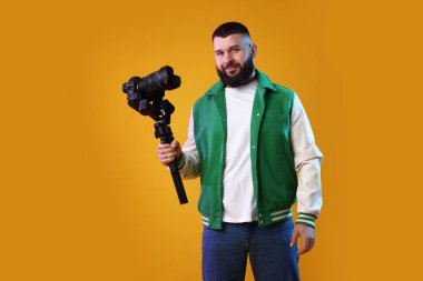 Sarı zemin üzerinde kamera olan titreşimli dengeleyici kullanan kameraman