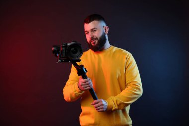 Kamerada çekim yapan kameraman, koyu arkaplandaki renk ışıklarına karşı titreşim dengeleyici kullanıyor.