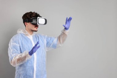 Modern teknoloji. Gri arka planda sanal ekran kullanan kulaklıklı bir doktor. Metin için boşluk