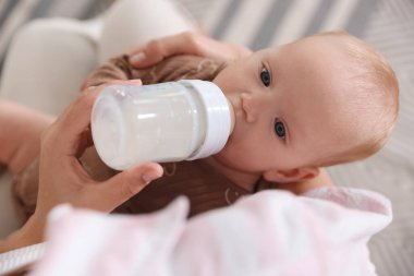 Anne bebeğini evde şişeyle besliyor.