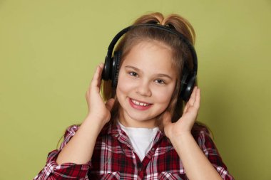 Zeytin arka planında kulaklık takan tatlı bir kız.