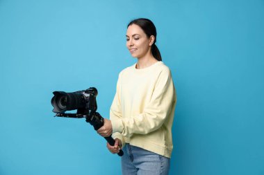 Açık mavi arkaplanda kameralı titreşim dengeleyici kullanan kameraman