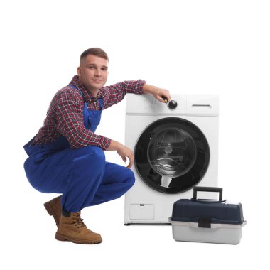 Beyaz arka planda çamaşır makinesi ve alet çantası olan üniformalı bir tamirci.