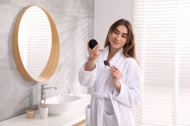 Bornozlu, yüz pudralı ve kapalı mekanlı güzel bir kadın.