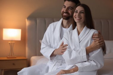 İçerideki yatakta bornozlu mutlu çift. Metin için boşluk