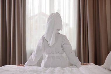 Bornoz giymiş, saçı havluya sarılı bir kadın.