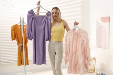 Kadın içeride menekşe ve pembe elbiseler arasında seçim yapıyor.