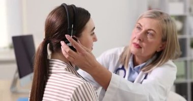 Duyma testi. Doktor klinikte hastanın işitsel kulaklığını ayarlıyor.