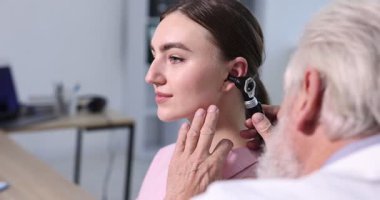 Duyma testi. Klinikte otoskopla hastaları muayene eden doktor..