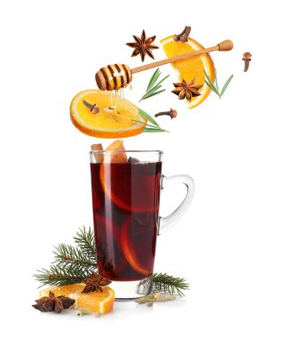 Sıcak şarap malzemeleri beyaz arka planda cam bardak sıcak içeceğe dökülüyor.