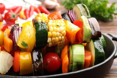 Ahşap masada lezzetli ızgara sebzeli şişler, yakın plan.