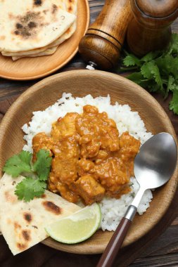 Pirinçli tavuk tikka masala, kişniş, kireç ve lavaş ahşap masada servis edilir.