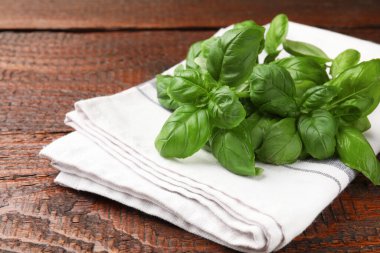 Taze fesleğen yaprakları ve peçete ahşap masada, yakın plan.