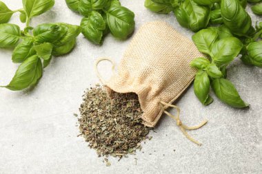 Açık gri masada taze ve kuru fesleğen yaprakları, düz yatıyordu.