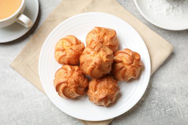 Lezzetli profiteroller, içki ve pudra şekeri açık gri masada, düz yatıyordu.