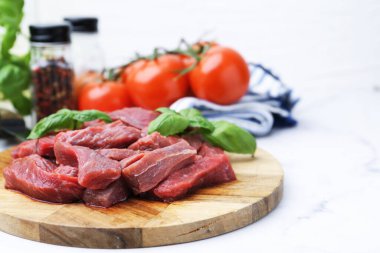 Çiğ et parçaları, fesleğen ve malzemeler beyaz mermer masada, yakın plan. Metin için boşluk