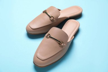 Açık mavi arka planda bir çift şık katır ayakkabısı, yakın plan.