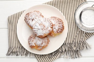 Beyaz ahşap masaya pudra şekerli leziz profiteroller.