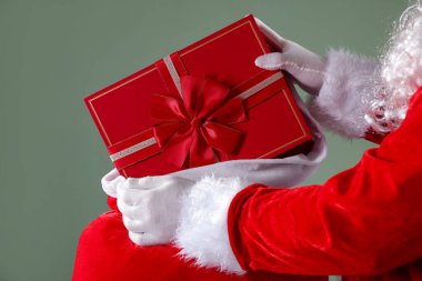 Noel Baba, gri arka planda çuvaldan hediyesini alıyor, yakın plan. Mutlu Noeller ve mutlu yıllar.